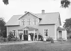 Familjen Andersson framför Älmekulla i Västra Ryd. Rimligtvis är det makarna Anders August Andersson och Josefina Olivia Johansson som står framför ingånen till verandan. Tiden är omkring 1915.