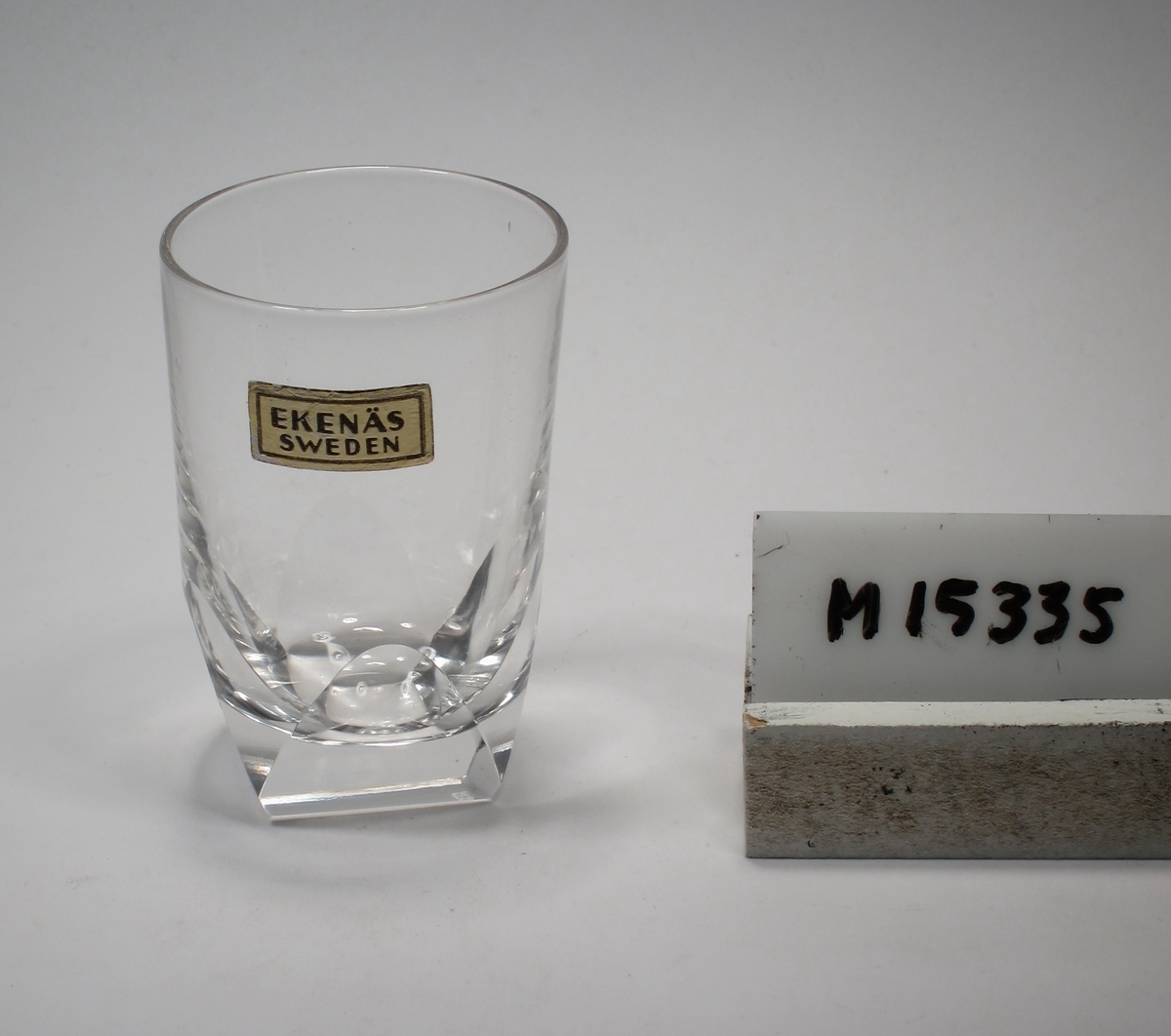 Snapsglas.
Beskrivning: Cylinderformat. Basen fyrsidig genom slipning. Nedtill fyra slipade halvovaler.
Färg: Ofärgat klarglas.
Mått. Ovan anges höjd samt övre diameter. Diameter botten: 23 mm.
Inskrivet i huvudkatalogen 1952.
Funktion: Snapsglas