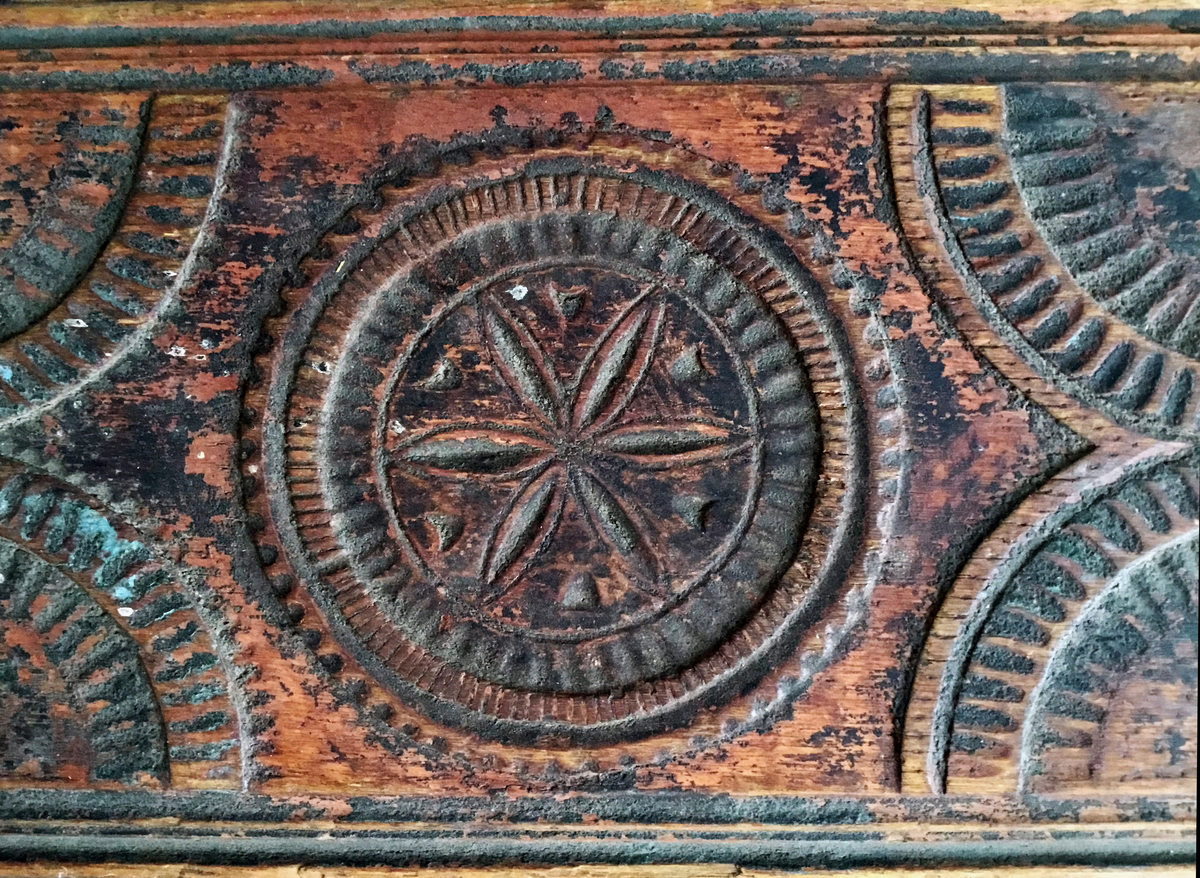 Mangletreet er malt rødt og sort. Karveskurd. Hestehåndtak, smal profil på sidene. Sikk sakk ornamentikk ved hestehåndtaket. Dekorert med sirkler og halvsirkler, og seksbladsroser i sirklene. Lærhempe i enden. Håndtaket festet med jernskruer.