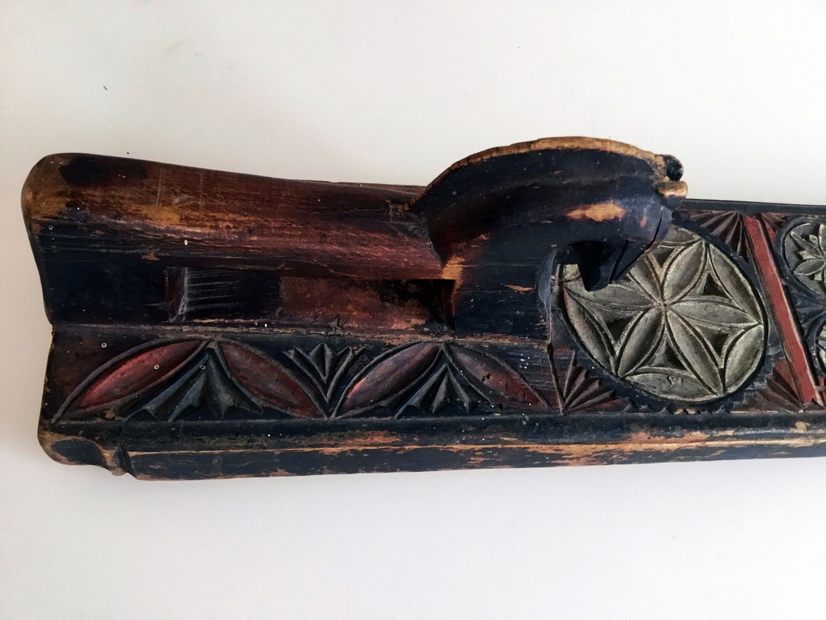 Mangletreet er malt rødt, sort og kvitt. Karveskurd. Hestehåndtak. Afrundet foran. Dekorert med store og små seksbladsroser.