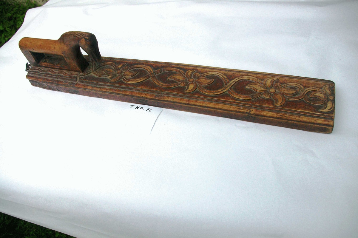 Mangletreet er malt brunt. Dobbelt ranke med seksbladete blomster innskåret. Hestehåndtak. Profiler på siden. Lærhempe bak.