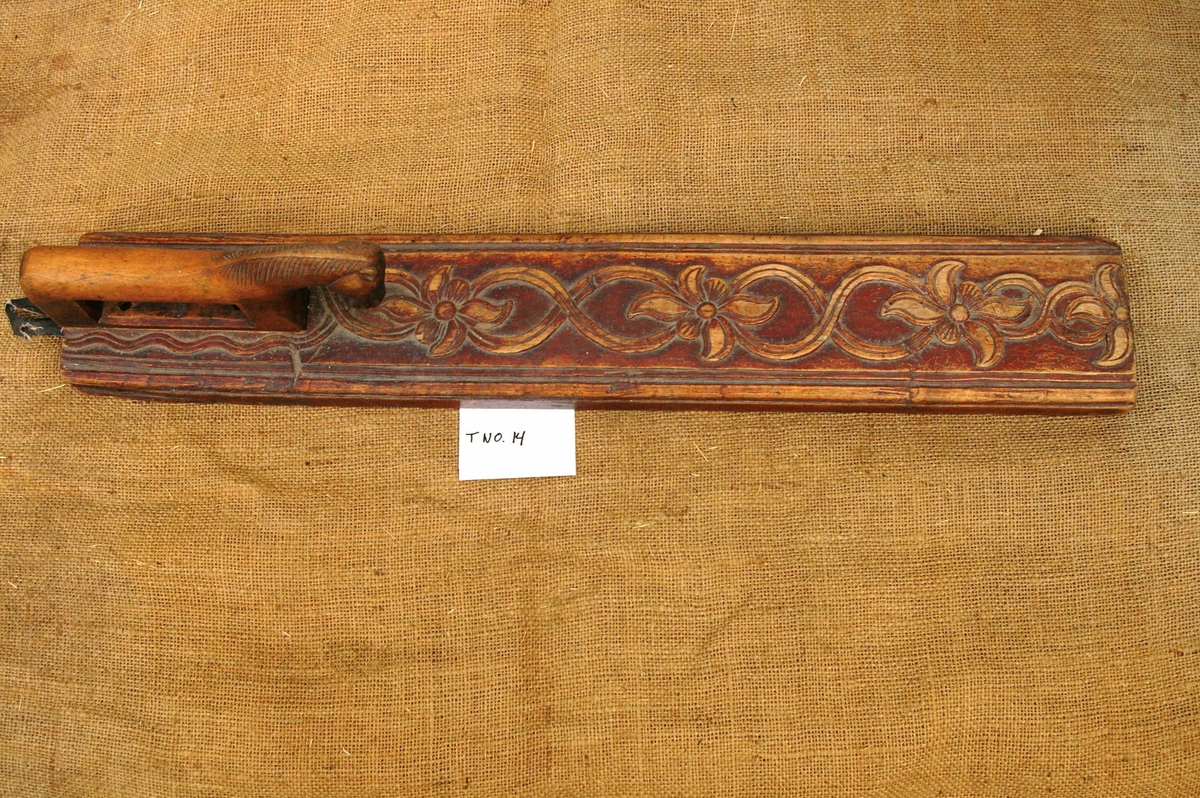 Mangletreet er malt brunt. Dobbelt ranke med seksbladete blomster innskåret. Hestehåndtak. Profiler på siden. Lærhempe bak.