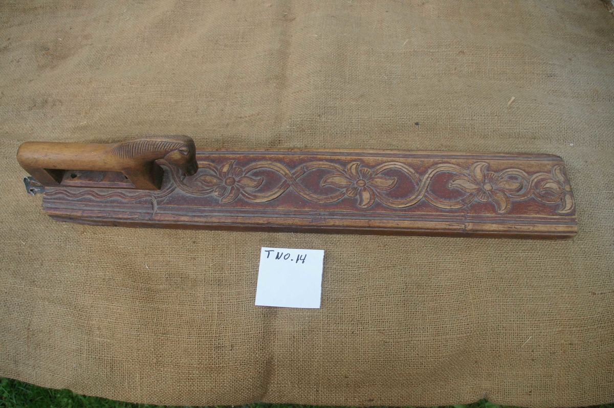 Mangletreet er malt brunt. Dobbelt ranke med seksbladete blomster innskåret. Hestehåndtak. Profiler på siden. Lærhempe bak.