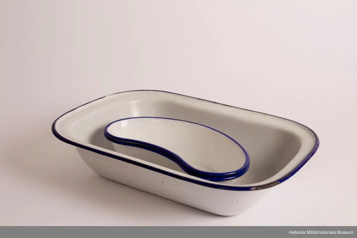 Ett djupt fat. rektangulärt, vit och med blå kanter. Emaljerad metall. Fabriksmärkt på undersidan. 30 cm.