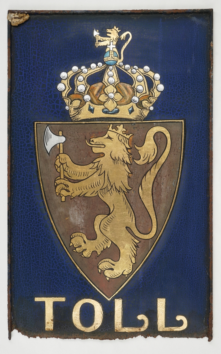 Bemalt metallskilt i rektangulær form. Riksvåpenet av 14.desember 1905 er påført i brun maling samt gullforgylling over "TOLL" i gullforgylling. Dette over en mørk blå bakgrunn. Skiltet er innrammet i en sort ramme, men det er usikkert om denne er original eller ikke.