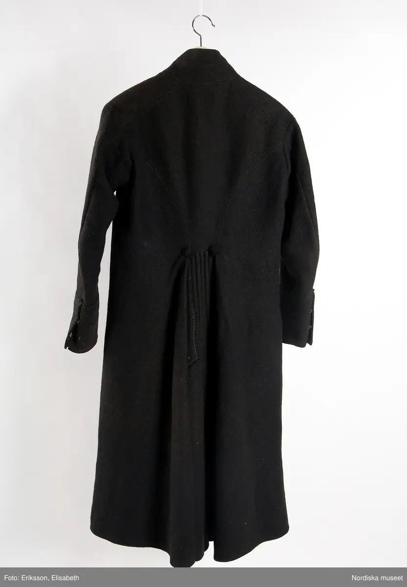 Mansdräkt i flera delar a-d.

a. Rock av svart vadmal
b. Röd väst
c:1-2 Vita strumpor
d. Knäbyxor av sämskskinn
Katalogkort finns.

a. Långrock av svart vadmal. Framstyckena/sidstyckena helskurna, ryggstycket smalt och kort,  avkuret i midjan, rikt veckat bakskört försett upptill med två ulltofsar och med pikerade klaffar en vid var  sida om skörtet. Svängda ärmar med 2 sömmar och blindslag med sprund oknäppt med 2 hakar och hyskor. Ståndkrage. Skoning av hemvävda ylleband i flera färger längs livets insidor, knäppning med hakar och hyskor.
"Dylika rockar tillhörde högtidsdräkten, vid mindre fester och till kyrkan brukades grå rockar af liknande snitt, ett snitt som gaf anledning till benämningen ´fiolen´för nysockenströjans ryggtafla ".
b. Väst av röd vadmal med ryggstycke av grovt oblekt linne i spetskypert. Hög ståndkrage och utvikta slag, med en uddklippt vadmalsremsa i kanten, dubbelknäppning med  vitmetallknappar, fästa på insidan med skinnremsa, knapphål tränsade med grönt ullgarn. 2 sidfickor med list. Foder av oblekt linnelärft, på kragens insida en bit av ryggtyget mitt bak.
c:1-2 . Strumpor slätstickade i tvåändstickning av fint vitt 1-trådigt ullgarn. Uppläggningsvarvet med rött och vitt ullgarn,  smal mönsterstickad överkant. Häl och tå av annat naturgrått garn. Mitt bak en sömmarkering med en avig maska. Vid anklarna broderade rombiska figurer i genombrutet mönster, kallas "löver" i rött ullgarn.
d. Knäbyxor av gult sämskskinn, med bred lucka med 5 knapphål, midjegjord knäppt med 2 knappar. Knapparna är av flera olika sorter av mässing, en av hängselknapparna av horn, 2 bak saknas. Midjegjorden fodrad med linnelärft. Knäsprund knäpps med 4 hakar och hyskor. Flikar vid sprunden uddklippta.
/Berit Eldvik 2010-01-08
