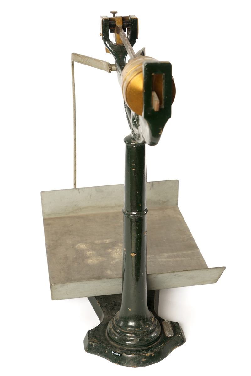 Balansevekt av metall bestående av fot,ben,vektarm og vektskål.