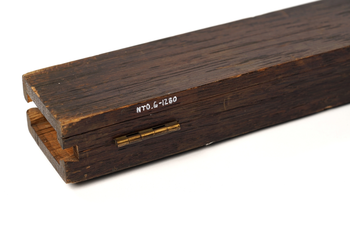 Trekasse med  hengslet lokk. Lokket lukkes med tre låsehjul