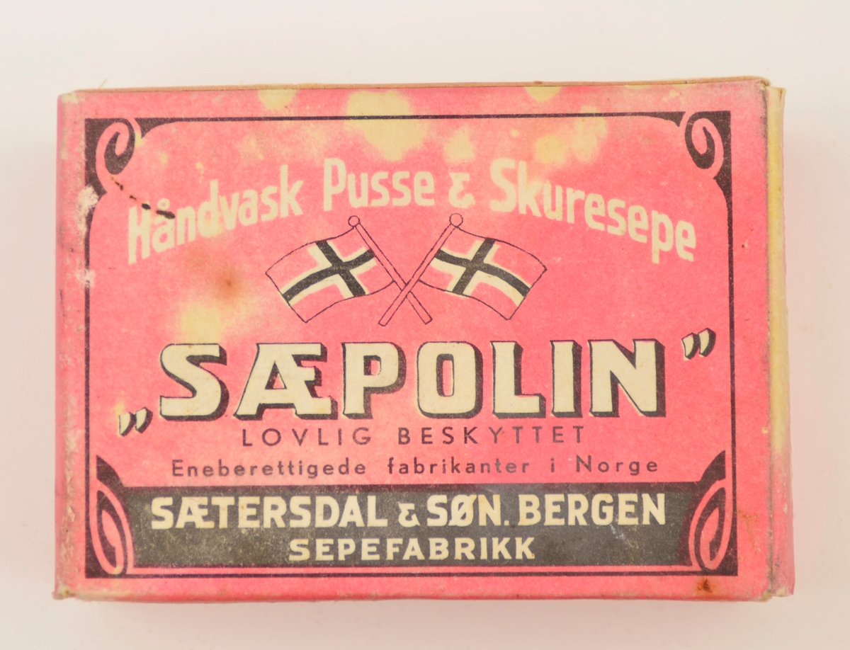 Såpe i original emballasje. Såpa er lyd og tung. Emballasjen er i papp, rosa botnfarge med kvit og svart tekst og teikning, m.a. norske flagg.
