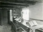 Kila sn, Sala.
Hembygdsgården, interiör av köket med bänk dukat träbord, dörr, bok, tallrikshylla m.m.