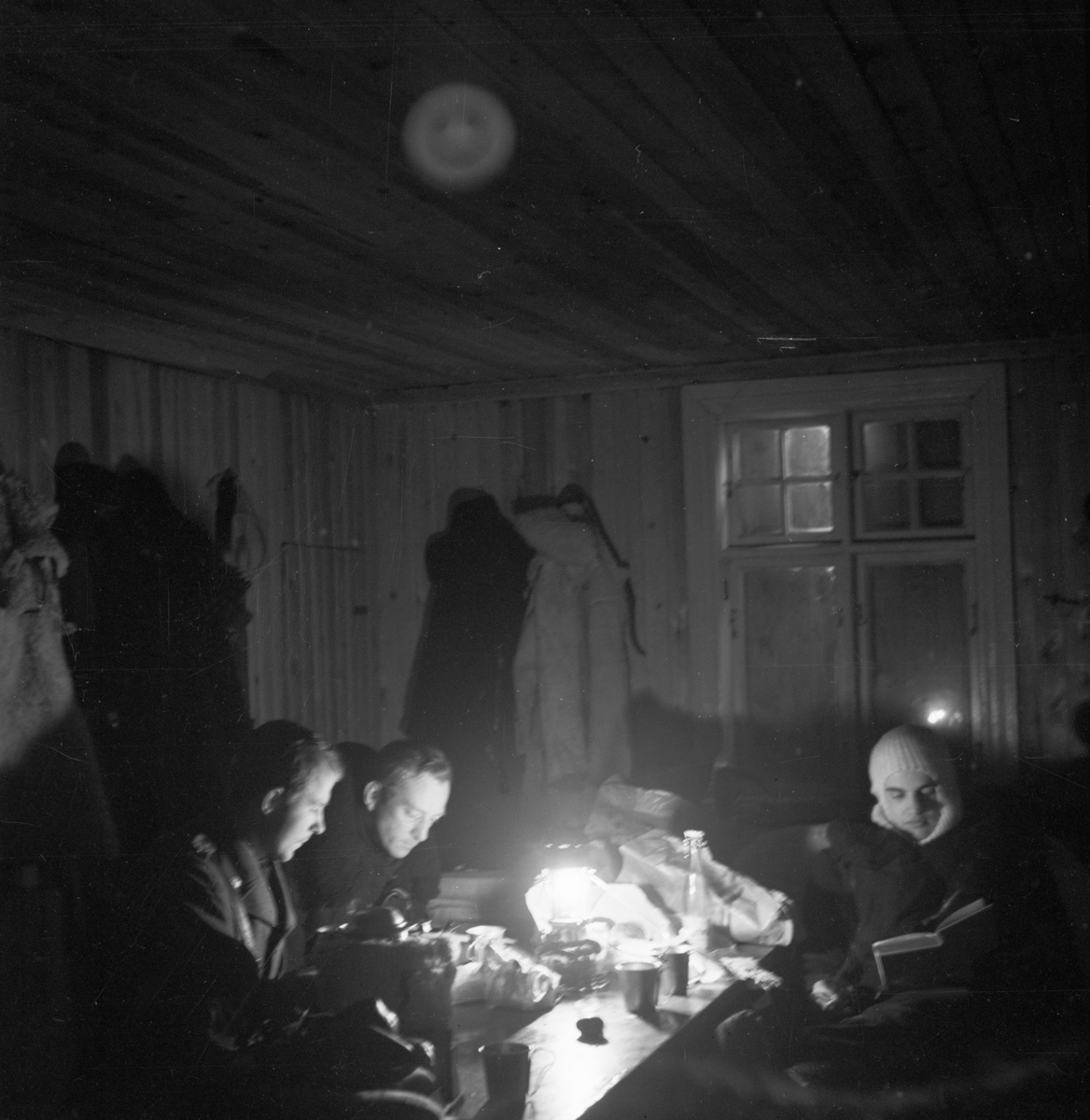 Beredskapsläge vid Svenska frivilligkåren i Finland, F 19. Tre militärer sitter vid lampa inomhus och väntar på larm från luftförsvarscentralen under 'Operation Pekka'. Från vänster Arne Frykholm, Åke Söderberg och Martin Wennerström.