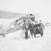 Flygförare från F 19 samt en kvinna framför flygplan J 8 Gloster Gladiator på flygfält på Kyrksjöns is i Ljusdal i början av januari 1940. Från vänster; Arne Frykholm, Einar Tehler, okänd kvinna, Martin Wennerström. Flygplanen flög senare vidare till Svenska frivilligkåren i Finland, F 19. I bakgrunden står flygplan Gloster Gladiator.