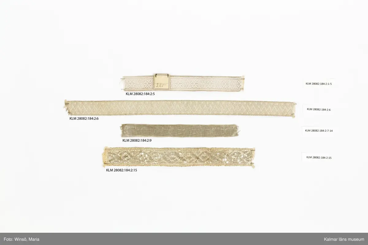 KLM 28082:184:2:1-15. Silverband, 15 stycken, av bomull och metall, silver, varierande mönster, längd och bredd. 6 olika sorters band. :1-5 Band, silvergalon, 5 stycken, silver, mönsterbård, silverblomma, sex linjer, korsande varandra och bildar en romb, mellan blommorna. (jmf. provkarta på KLM 28082:184:1:1-2). :5 Band med etikett i kartong, med siffrorna 3,25 i blyerts. :6 Band, silver, med triangelmönster. :7-14 Band, 8 stycken, baksida, helt i silver, framsida, med invävd bomullstråd, mönsterbård och silverkant. :15 Band, med bred sivertråd. Framsida, mönsterbård, åttor, som bildar lång fläta. Baksida, helt i silver. Etikett av papper runt bandet med nummer och längd, skrivna i bläck och blyerts.