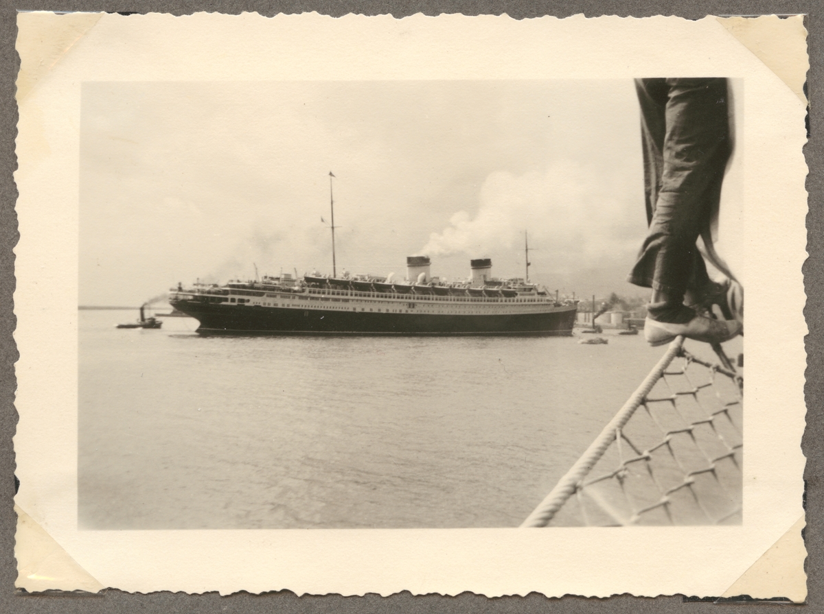 Bilden visar det italienska passagerarfartyg SS Rex som anlöper en hamn med hjälp av flera bogserbåtar.