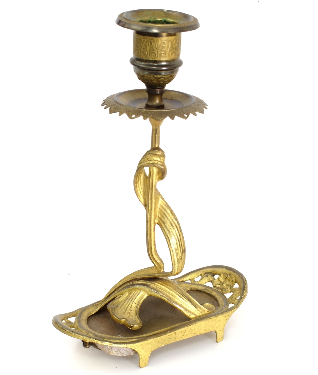 To like lysestaker av messing og polert stein. Avlang fot på fire ben med rette  langsider og avrundede, oppbøyede  kortsider. Skaftet vokser som to sammenflettede blad opp fra en  bladklynge på foten. Holderog dryppeskål med profileringer og bladornamenter.