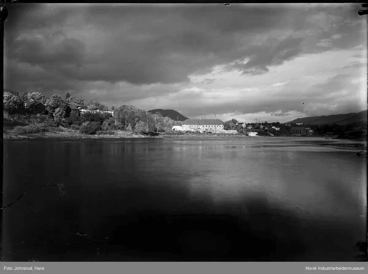 Fylkesutstillingen Kongsberg 1924. Utsikt myntverkets lokaler, bygningen som huser Fylkesutstillingen. I bakgrunnen boligbebyggelse og i forgrunnen vann.
