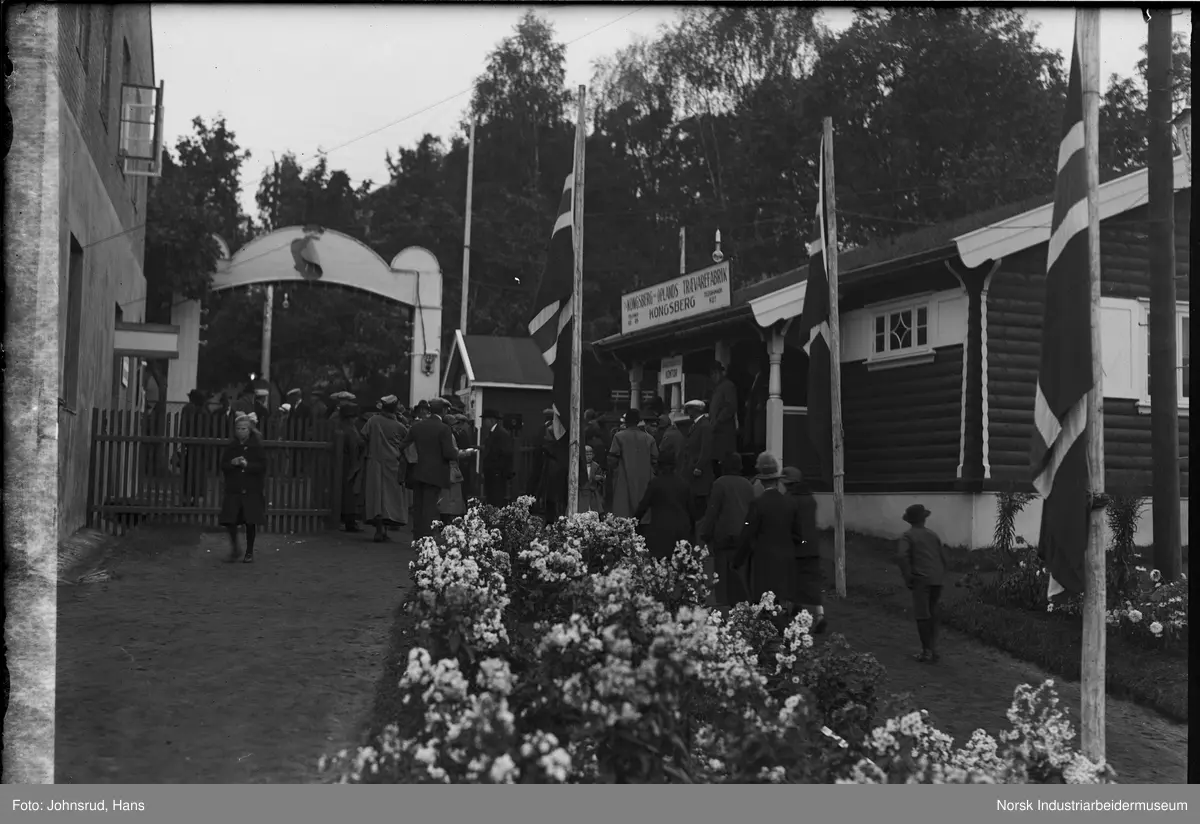 Fylkesutstillingen Kongsberg 1924. Mennesker på vei ut gjennom port. Lokale for Kongsberg og Oplands Trævarefabrikk til høyre.