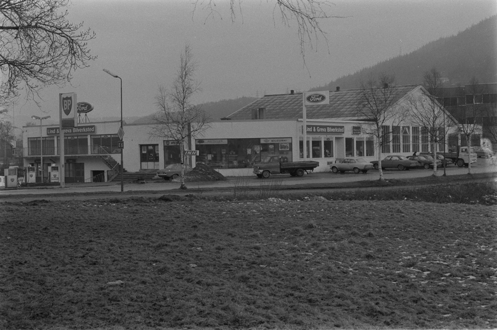 Lind & Greva i Mosjøen, Mars 1975. Markering i forbindelse med 20 år som Ford forhandler.
Bygningene sett fra sør mot nord, Skjervgata i forgrunnen.