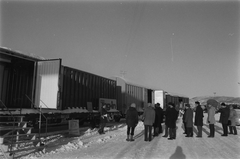 Konferanse om jernbanen. Informasjon og demonstrasjon av transport ved jernbanen. Demonstrasjon av container som blir flyttet fra tog tvil bil. Containeren har logoen Tog-inn. Fra innføringen av containere ved jernbanen?