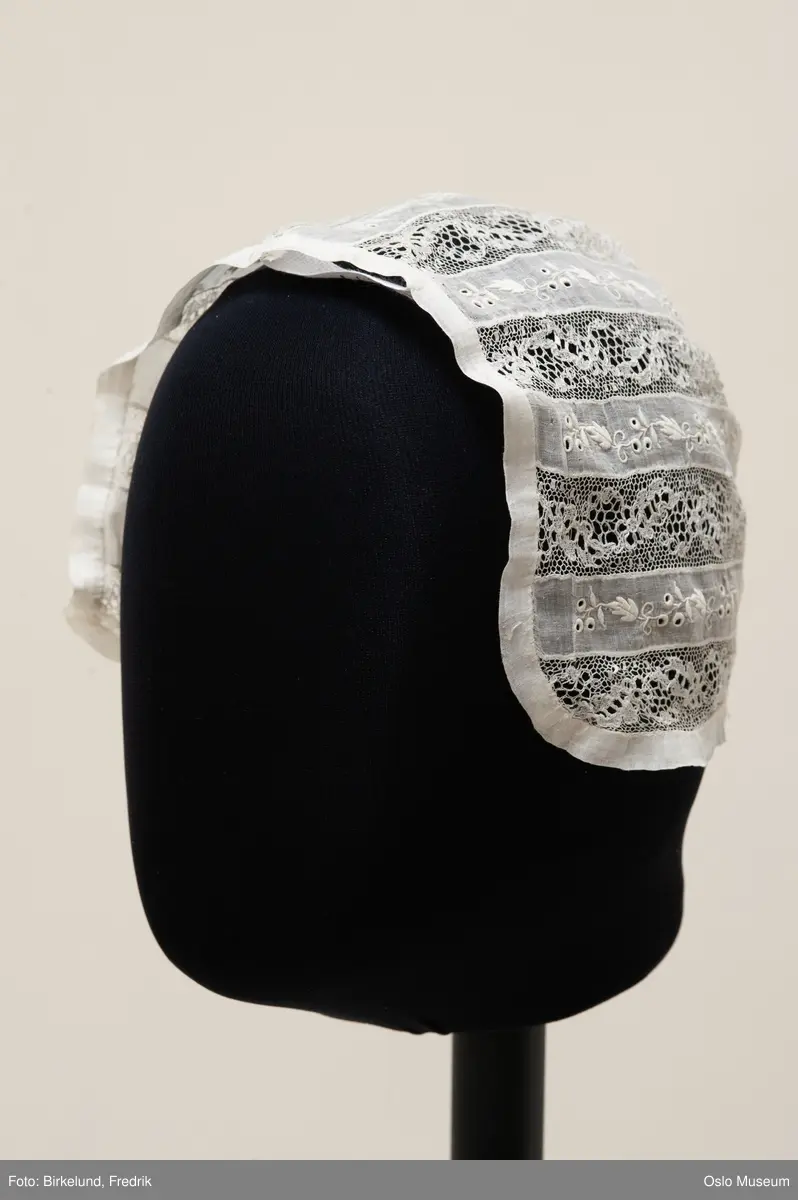 Barnelue sydd sammen av to ulike blonder, en brodert og en kniplet.
Kant rundt sydd av tynt bomullsstoff
Størrelse: ca. 6 mnd.