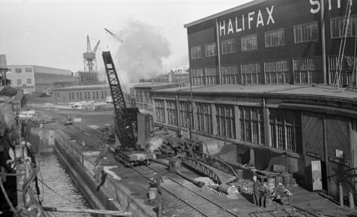 Tørrdokken i Halifax fylles. Skipsverftet med kraner og arbeidere til høyre og i bakgrunnen. Suderøy gjøres klar til avgang.