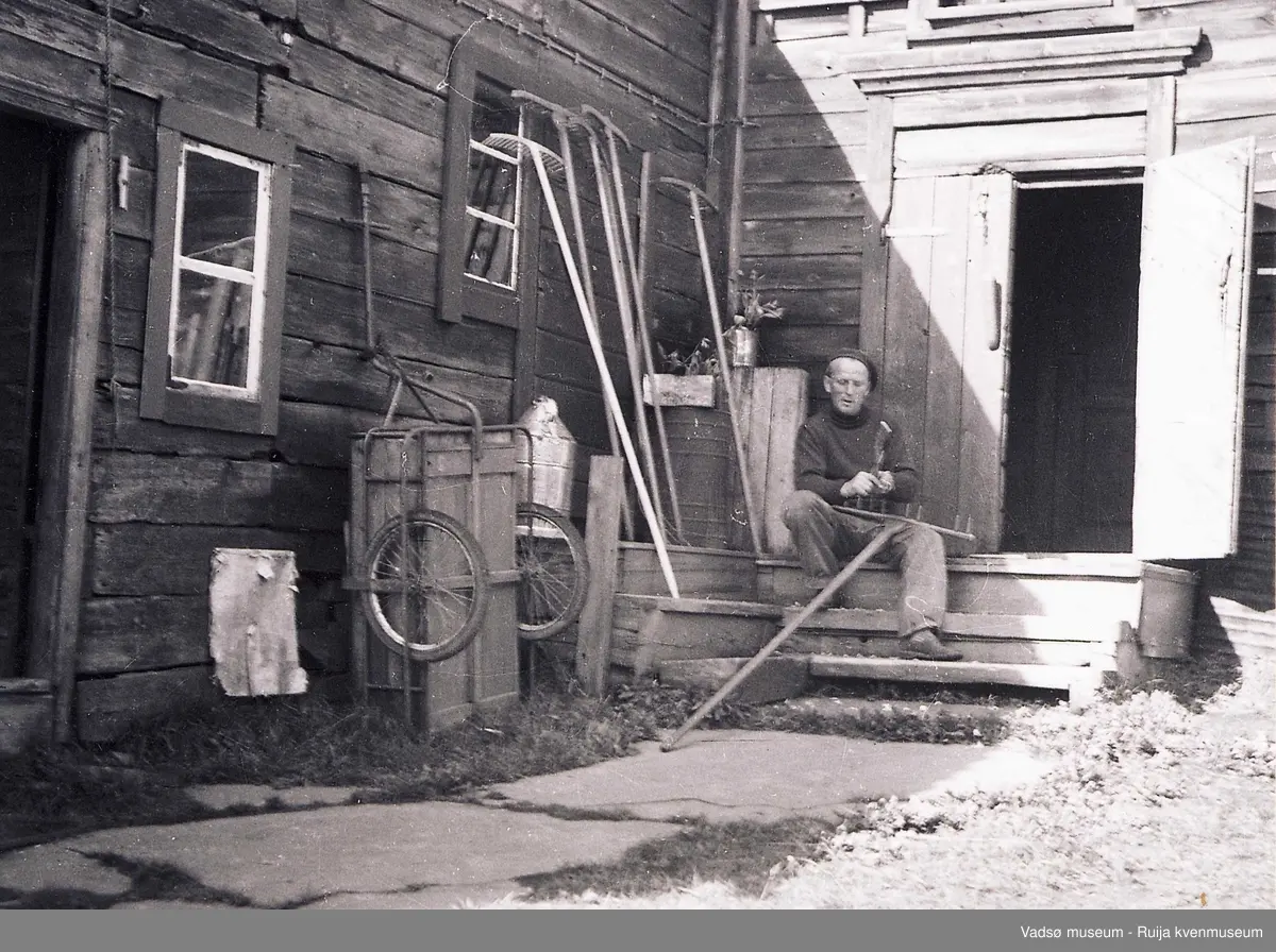 Alf Tuomainen reparerer river. Sitter i døra til verksted og bakeri i Tuomainengården. Ca 1950-1960-tallet.