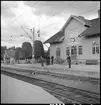 Resande och stationskarl utanför Gårdsjö station. I bakgrunden flaggas det på halvstång.