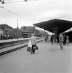 Perrongen på Eslöv järnvägsstation. Elektrisk drift installerades 1933. Förekomsten av militärer bland de resande gör det troligt att bilden är tagen under krigsåren. Till vänster syns ett flertal bussar av 1930-tals modell. Till vänster skymtas också Stadshotellet.