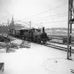 Statens Järnvägar SJ 1856-1956. 100-årsjubileum. Tåg med gamla lok och vagnar vid Tegelbacken på väg mot Stockholm Central, på sträckan mellan Riddarholmen och Stockholm Central. Oxelösund-Flen-Westmanlands Järnväg OFWJ lok 8. .