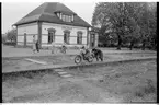 Stationshuset i Åsbo-Össjö. Stationen nedlagd 1953-06-10. Barn med motorcykel på plattformen. Spåren är borttagna.