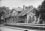 Lammhult station. Ljusbrunt med mattgula knutar, lister o foder, gröna dörrar o fönsterbågar. Taket rödbruntskiffer. Skyltarna mattgula som listerna med brun stil. Staket t höger rött m vit gränd. röd tegelskorsten.