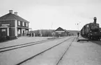 Örsundsbro stationshus med persontåg vid plattform.