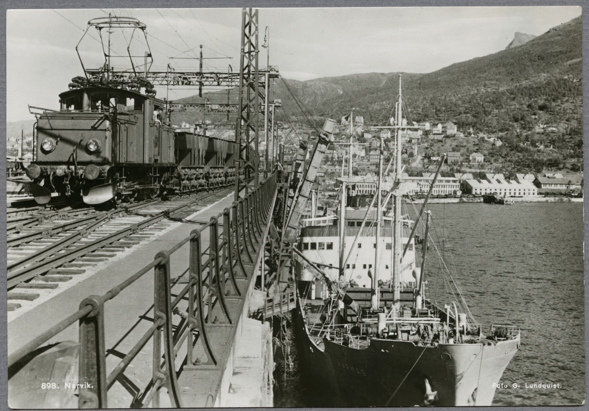 Malmhamnen i Narvik med "M/S Karmas" vid kaj. På bron syns ett ellok med malmvagnar. Luossavaara-Kiirunavaara Aktiebolag, LKAB F 29. Malmvagnar.