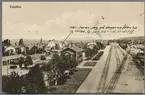 Stationsmiljö i Vansbro med vagnar och stad i bild.