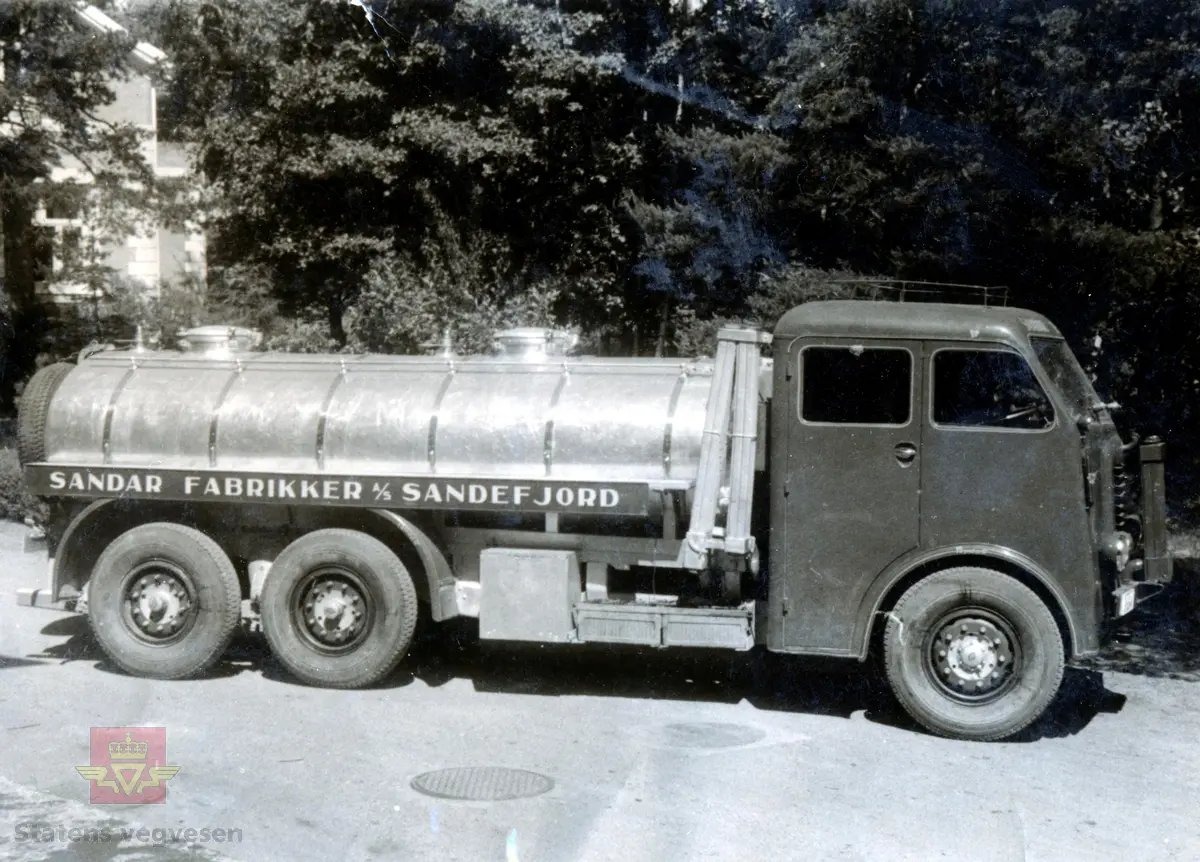 Tankbil fra 1939, i transport for Sandar Fabrikker A/S. Ukjent fabrikat. Førerhuset er bygd hos Gjerpe & Moholdst Karossefabrikk, Kilgata i Sandefjord. Bildet er tatt under krigen da det er påmontert gassgenerator, i front sees generatorkjøler. Bileier Chr. F. Petersen har tatt bildet.