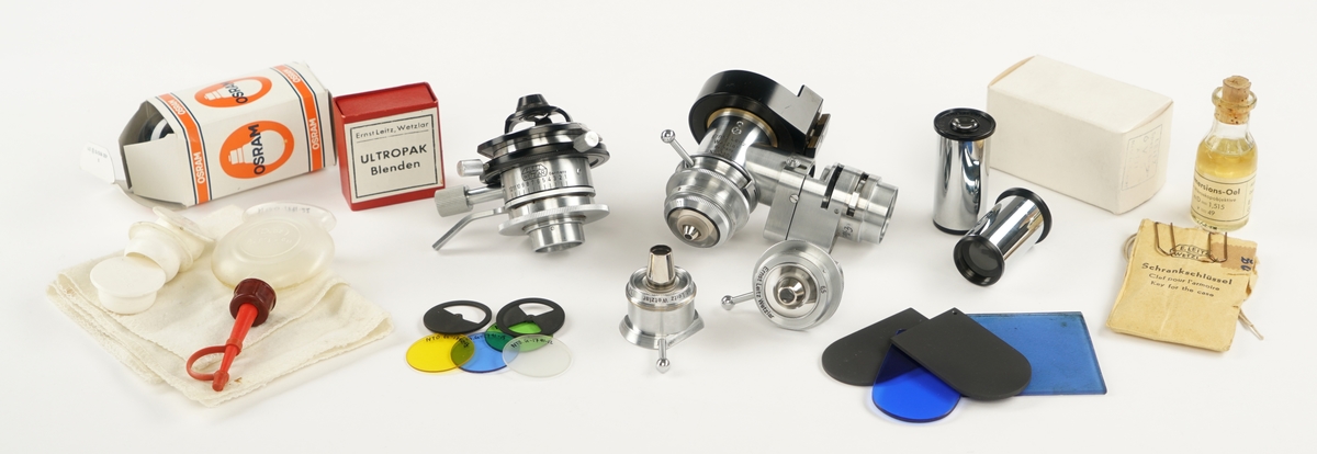 Mikroskop med tre okkularer samt tilkoblet to strøm/lyskilder og medfølgende utstyrskasse i tre som inneholder:
Tre beskyttelseshetter av plast
To okkularer
Tre objektbord
Syv objektfiltere
fire ulike linser
En glassflaske med Immersions olje
En plastpipette for antatt olje
To lyspærer pakket i pappesker
Åtte blendere pakket i pappeske
En nøkkel til kassen pakket i papirpose
En pusseklut