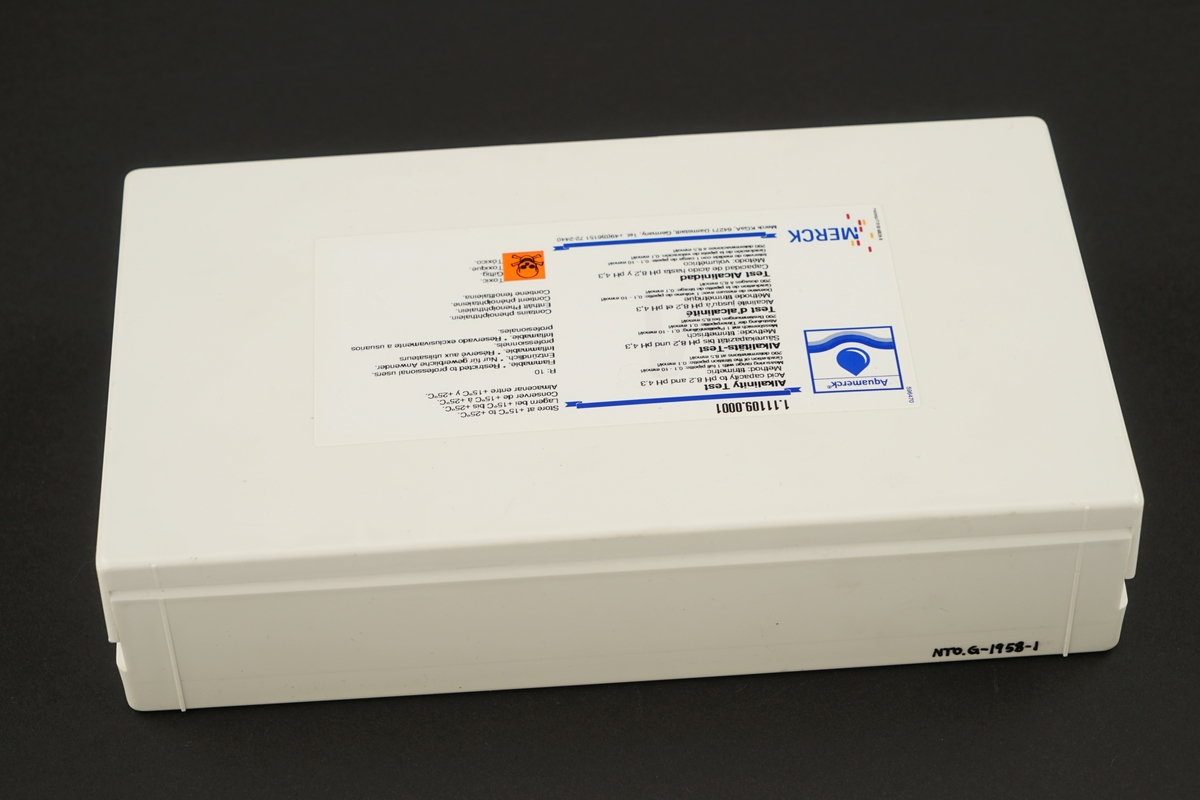 Plastboks med lokk inneholdende  fire plastflasker med skrukork med kjemikalier, ett målebeger, en sprøyte og en pipette, samt to typer bruksanvisning.