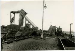 Tippning av aska från ångloken över till godsvagnar.
Loket i