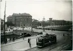 Malmö Central järnvägsstation sedd från gatusidan och med spårvagnstrafik på gatorna. Spårvagnarna delar utrymme med hästdragna kärror.