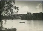 Roddbåt på sjön, stationshuset i Ängelsberg ses i bakgrunden.