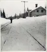 Stationsområde med vy på bangård och personal som utför snöröjning.