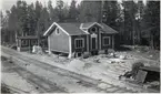Långsjön under ombyggnad. Långsjö-Pelle till vänster framför huset tillsammans med övrig arbetskraft. Kuren till vänster i bild.