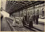 Banhallen vid Stockholm centralstation, 1893 eller 1894. 
Damerna på bilden är anställda vid byrån för kombinerade biljetter. 

Från vänster: Fröken Elin Lundberg, död omkring 1900, dotter till J. H. Lundberg, Fröken Anna Wallin, Fröken Ellen Ström, syster till trafikdirektör E. Ström och gift med Stins K. A. Smedmark Hudiksvall, Stationsskrivare E. F. Björkman, Trafikdirektörsassistenten F. Rydbeck, sedemera trafikinspektör, död 28/2 1911, Fröken Victoria Westerlund, Kontorsskrivare O. A. Norbäck, död 1919 samt Stationsinpektor W. H. Kock, Död 1917.