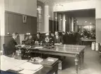 Telegrafexpeditionen vid Stockholm Central 22/12 1910.
Från vänster vid apparatborden; Stk Malmqvist (ev står det Wahlqvist, texten är svår att tyda), Kb Eskil Svensson, Stk Linder, eo Sts Rudolf (ev Adolf) Skeppstedt, Kb Albihn, ex skrivbiträde Zandén, eo Stk Blomberg, Sts Christensson, Verkmäst. Santesson, Kb Alb. Carlsten, eo Stk Danielsson, Tlt Ågren (ev Agrell - svårtydd text), telbud Berggren, Tågledarna vid skrivbordet till vänster är G. Dahlström och Nylinder.