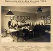 Dalslands Järnvägs styrelse 1929. Styrelsemöte 20/4 1929.
11 herrar kring ett bord:
Kapten C G Högman, trafikchef.
E Sem, konsul, Vice ordförande, verkställande direktör
Axel R Jansson, bruksägare.
Alf L Torpp, kaptein.
A Aakre, Skolebestyrer, ordförer, Haldens kommuns representant.
Ola Sveen, byfogd, Norska statens representant
Karl Mellén, häradshövding, ordförande. 
Arnold Larsen, kamrer, sekreterare.
Axel von Sneidern, landshövding, Svenska statens representant.
Albert Luthander, Ingeniör.
Louis G Övergaard, disponent.