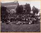 Personal och familjer vid UGJ vid Stora Hallen i Älvkarleö. Bilden fotograferad mellan år 1900-1905. Bilden är daterad genom att Stora Hallen byggdes år 1900, och unionen med Norge upplöstes 1905. Nere till vänster i bild står en pojke med en unionsflagga.  VD Magnus Fick vid UGJ slutade år 1909.