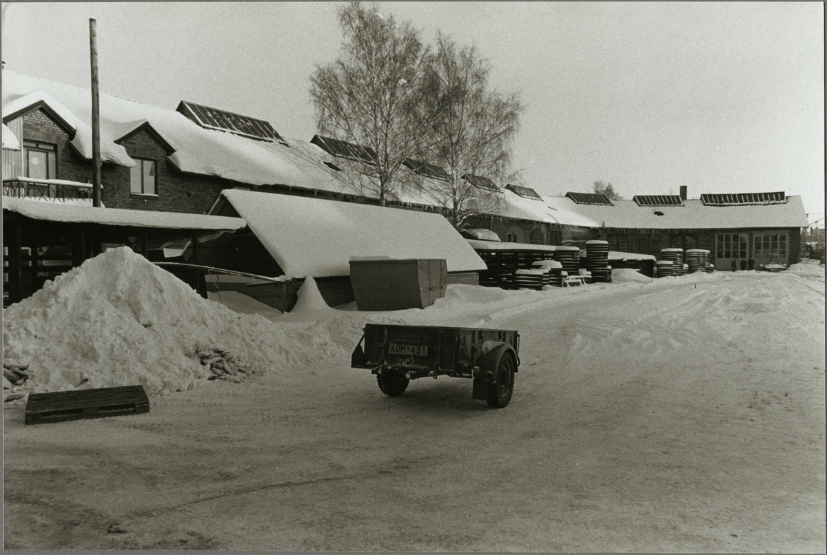 Släpvagn framför garage vintertid.