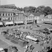 Vy över Stora torget i Linköping med pågående torghandel. Året är 1965 och ännu kan man behändigt parkera sin bil på torget.