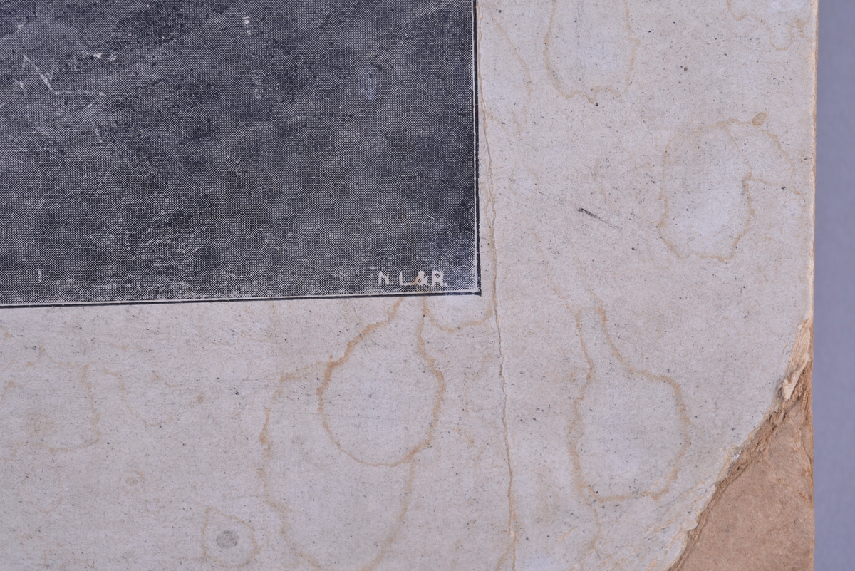 Rektangulær plansje av hvitt papir festet på kartong. Rektangulært motiv som er sentrert i midten av plansjen. Motivet er trykt i svart- hvitt. Midt på øverst på plansjen er det to hull for oppheng.  Det er trykt tekst på undersiden av motivet i form av svarte trykte bokstaver.