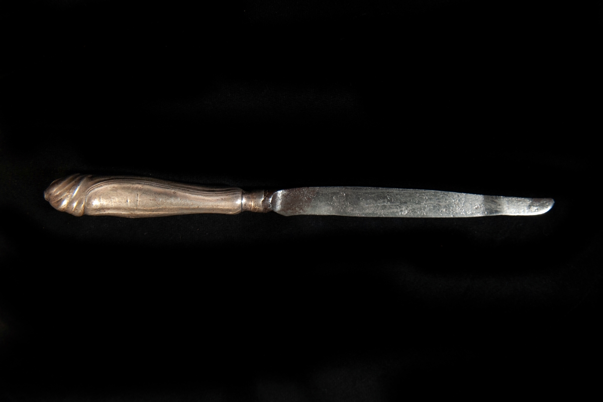 En spetsig kniv med skaft av silver i rokoko. Mycket otydliga stämplar. 
Tillverkad i Jönköping.